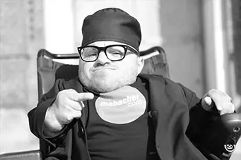 Foto von Martin Mabacher im Rollstuhl. Er zeigt den Mittelfinger.